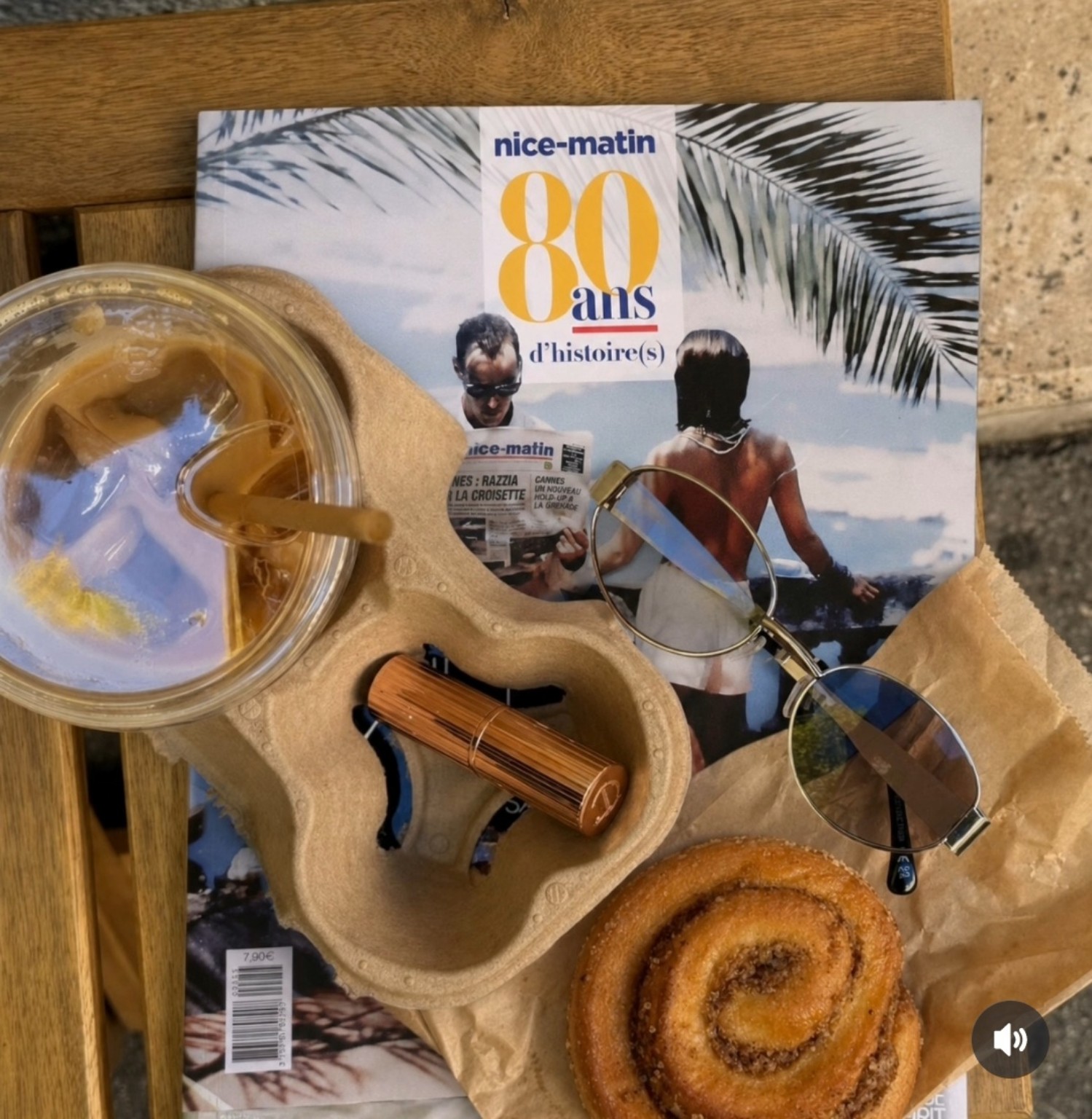 Café glacé, viennoiserie et Nice-Matin sur une table en bois